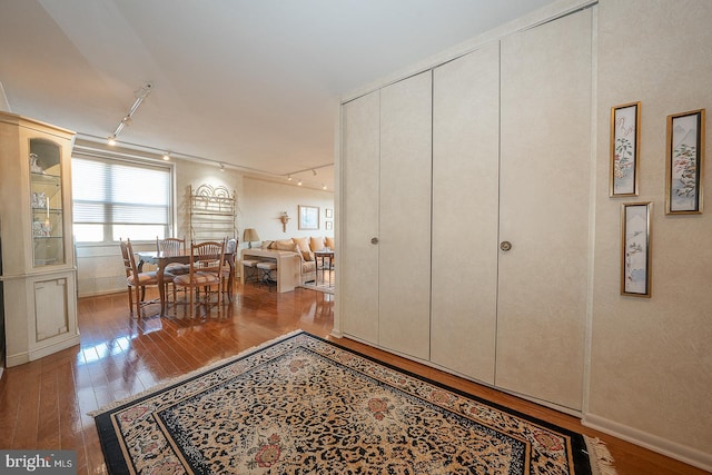 interior space with baseboards, hardwood / wood-style floors, and track lighting