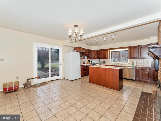 kitchen with hanging light fixtures, stainless steel dishwasher, a kitchen island, white fridge, and a chandelier