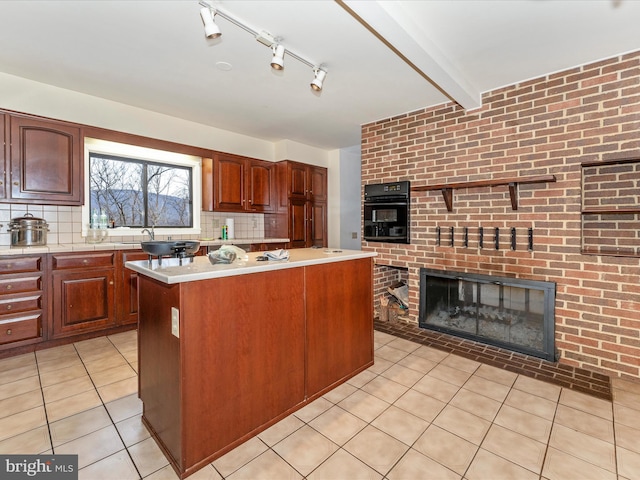 kitchen with tasteful backsplash, a brick fireplace, beam ceiling, a center island, and oven