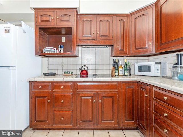 kitchen featuring tile counters, light tile patterned flooring, white appliances, and backsplash