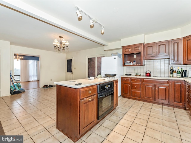 kitchen featuring an inviting chandelier, white refrigerator, backsplash, oven, and light tile patterned floors