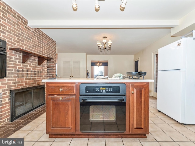 kitchen with light tile patterned flooring, oven, a fireplace, a notable chandelier, and white fridge