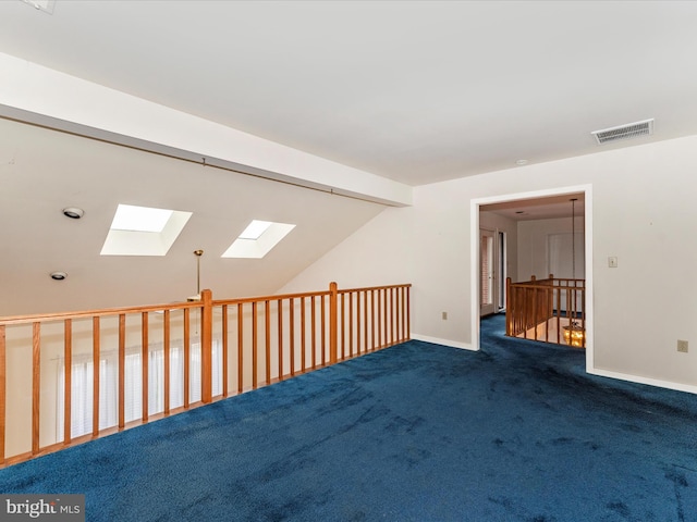 carpeted empty room featuring vaulted ceiling with skylight