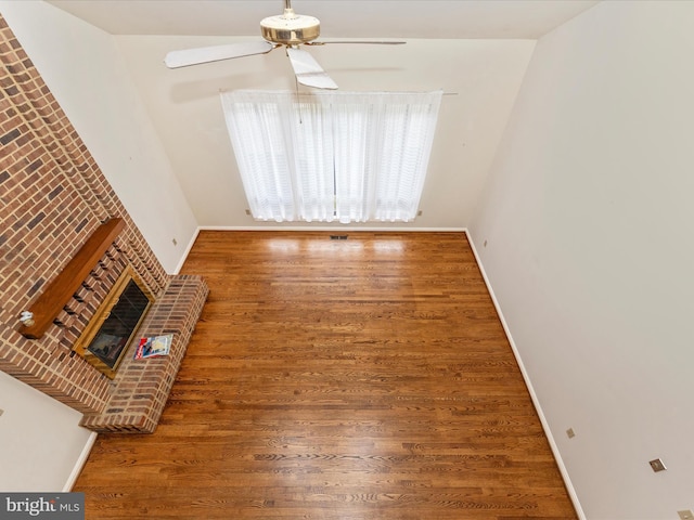 empty room featuring a fireplace, dark hardwood / wood-style floors, and ceiling fan