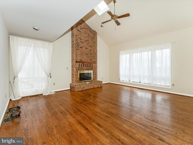 unfurnished living room with a skylight, ceiling fan, a brick fireplace, high vaulted ceiling, and hardwood / wood-style flooring