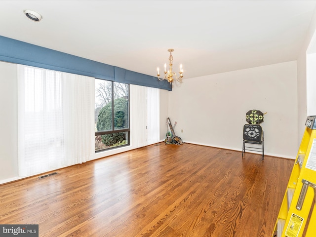 unfurnished room with hardwood / wood-style flooring and an inviting chandelier