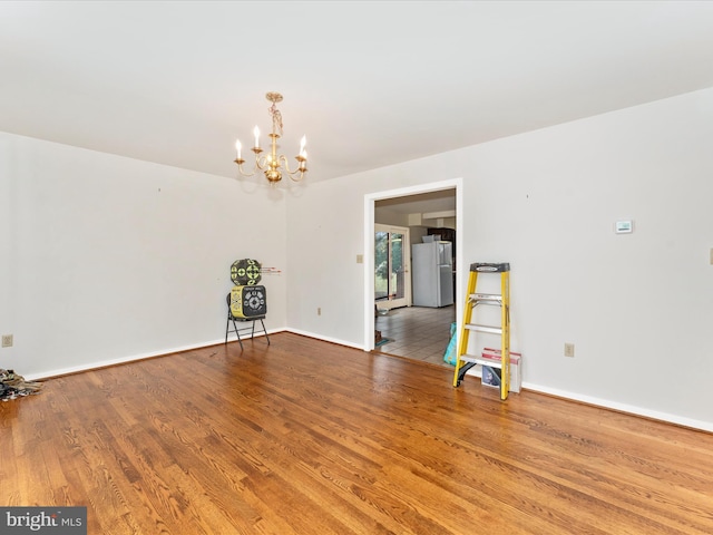 unfurnished room featuring hardwood / wood-style flooring and an inviting chandelier