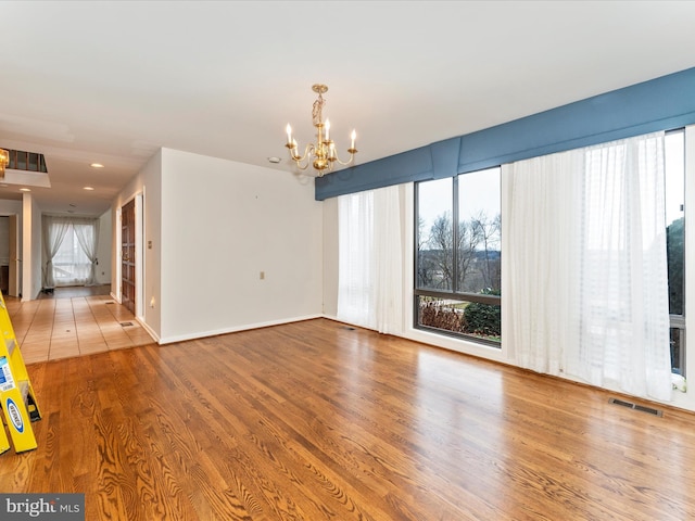 empty room featuring a chandelier and hardwood / wood-style flooring