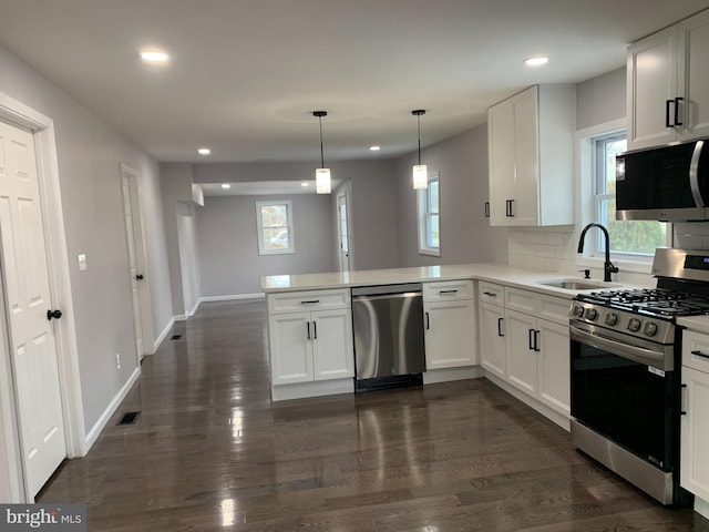 kitchen with sink, tasteful backsplash, white cabinetry, kitchen peninsula, and stainless steel appliances