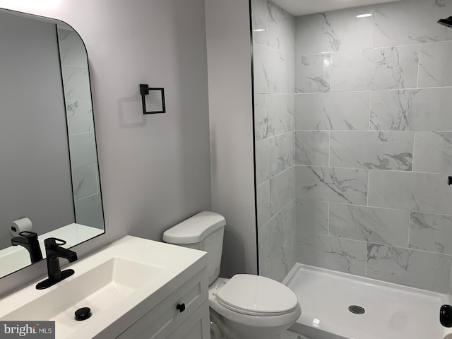 bathroom with vanity, toilet, and a tile shower