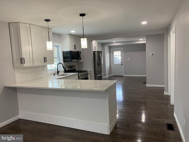 kitchen with kitchen peninsula, appliances with stainless steel finishes, decorative backsplash, sink, and white cabinetry