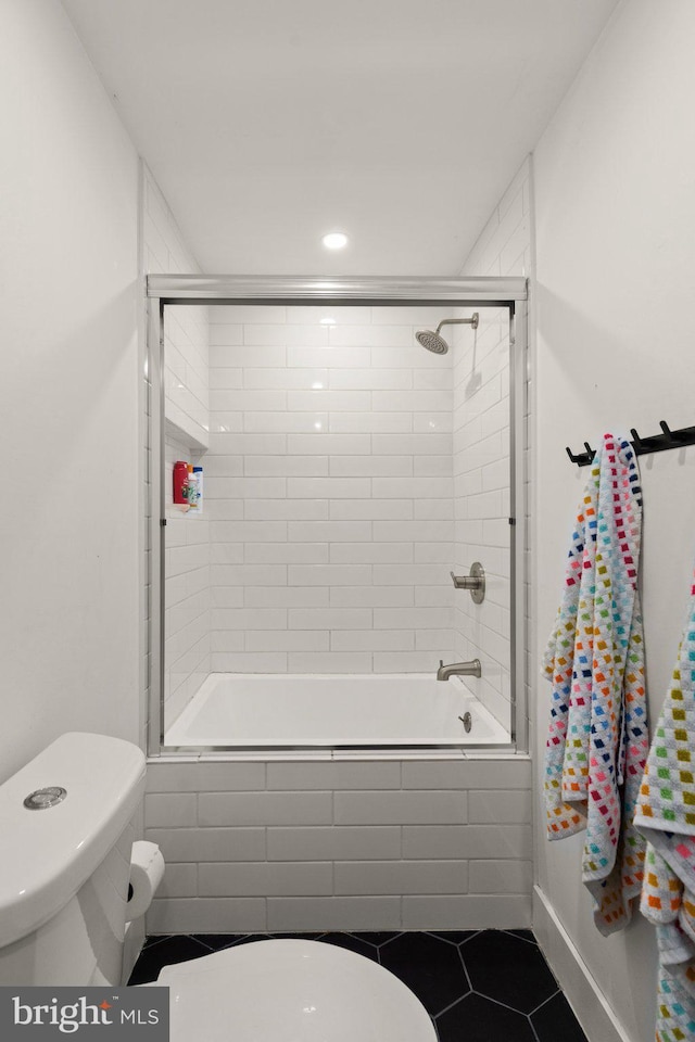 bathroom featuring combined bath / shower with glass door, tile patterned floors, and toilet