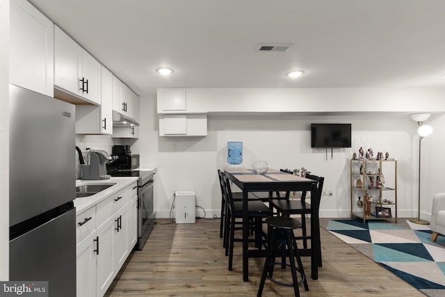 kitchen with tasteful backsplash, dark wood-type flooring, white cabinets, and stainless steel appliances