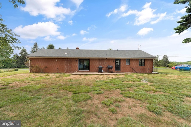 rear view of house featuring a lawn and a patio