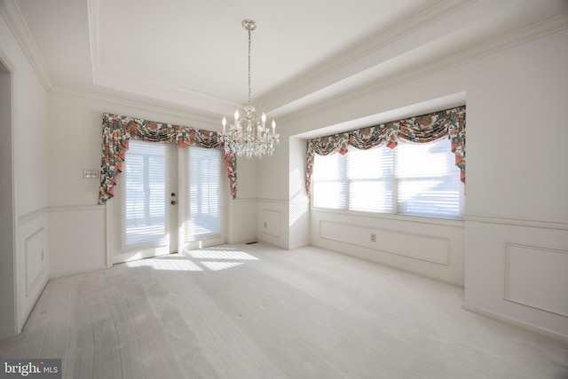 unfurnished room featuring an inviting chandelier, ornamental molding, and a raised ceiling