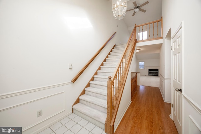 stairs featuring hardwood / wood-style flooring, ceiling fan, and a high ceiling