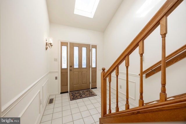 tiled foyer with lofted ceiling with skylight