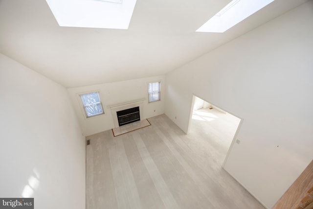 unfurnished living room with light hardwood / wood-style flooring and lofted ceiling with skylight