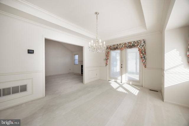 unfurnished dining area with a notable chandelier, a tray ceiling, crown molding, light carpet, and french doors