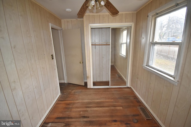 unfurnished bedroom featuring a closet, wood walls, and ceiling fan