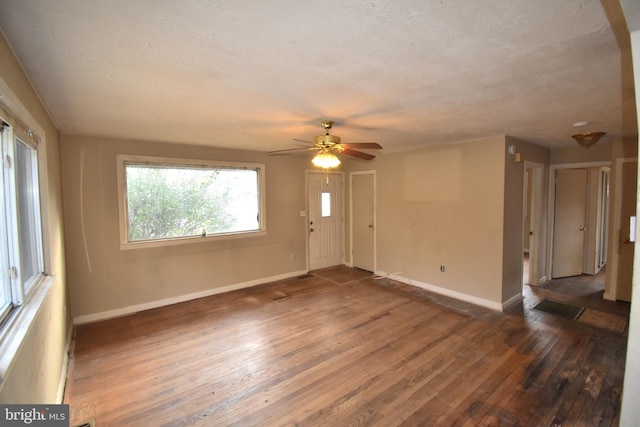 empty room with a textured ceiling, ceiling fan, and dark wood-type flooring