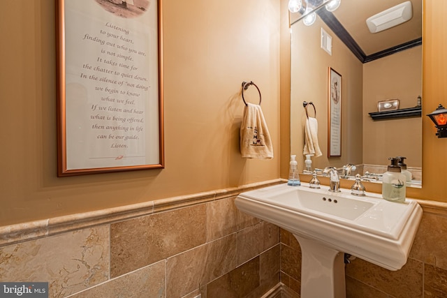 bathroom featuring tile walls, crown molding, and sink