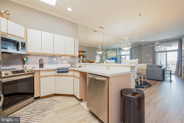 kitchen featuring ceiling fan, light hardwood / wood-style flooring, stainless steel appliances, and ornamental molding