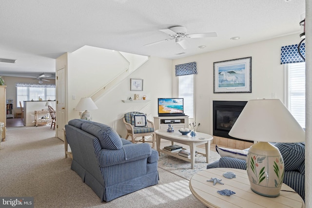 living room featuring light carpet, ceiling fan, and a textured ceiling