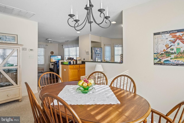 dining area with ceiling fan with notable chandelier and light carpet