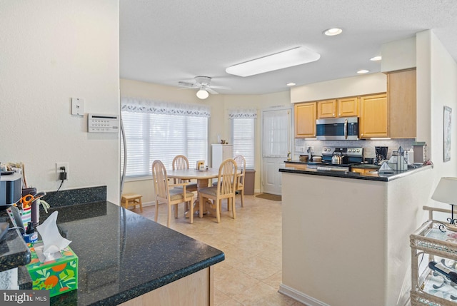 kitchen featuring ceiling fan, light brown cabinets, a healthy amount of sunlight, kitchen peninsula, and appliances with stainless steel finishes