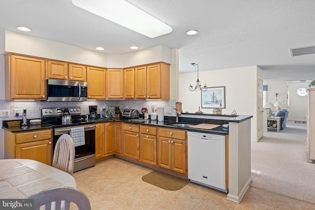 kitchen featuring light carpet, stainless steel appliances, sink, pendant lighting, and a chandelier