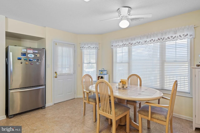 tiled dining space with ceiling fan and a textured ceiling