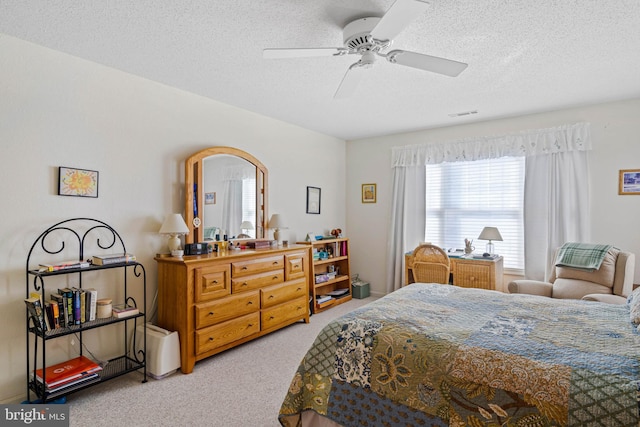 carpeted bedroom featuring ceiling fan and a textured ceiling