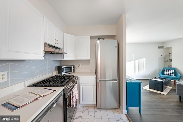 kitchen with tasteful backsplash, white cabinetry, and appliances with stainless steel finishes