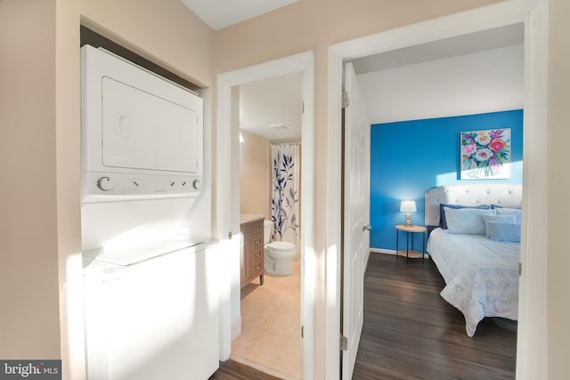 laundry area with stacked washer and dryer and tile patterned floors