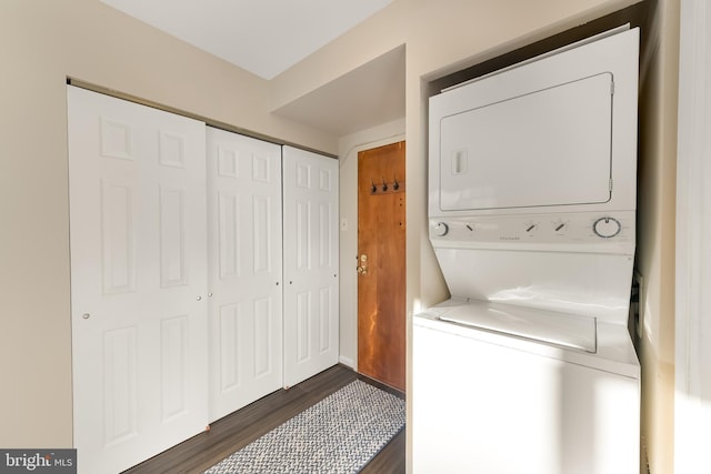 clothes washing area featuring dark hardwood / wood-style flooring and stacked washer / drying machine