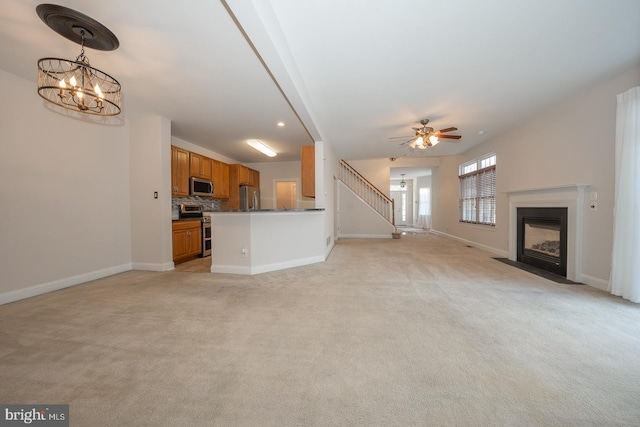 unfurnished living room with ceiling fan with notable chandelier and light carpet