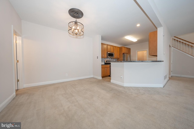 kitchen with kitchen peninsula, decorative backsplash, hanging light fixtures, appliances with stainless steel finishes, and light carpet