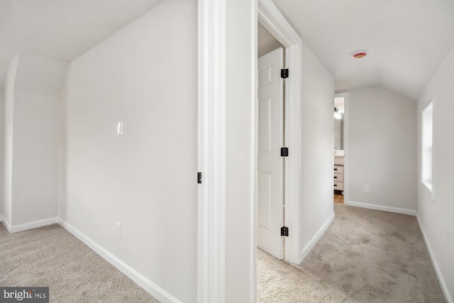 corridor featuring light carpet and lofted ceiling