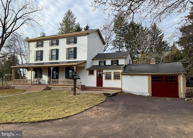 view of front of property featuring an outbuilding, covered porch, a front yard, and a garage