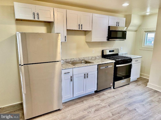 kitchen featuring stainless steel appliances, white cabinetry, sink, and light hardwood / wood-style floors