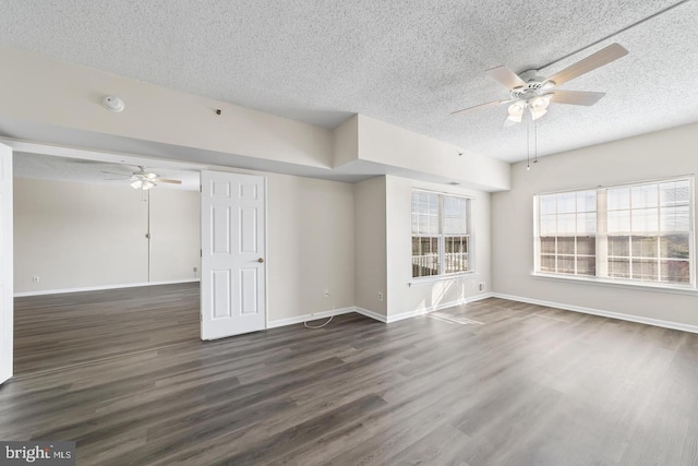 empty room with ceiling fan, dark hardwood / wood-style floors, and a textured ceiling