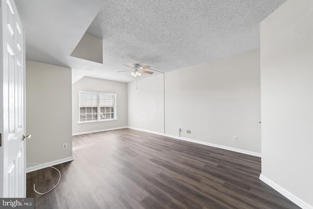 spare room with ceiling fan, vaulted ceiling, a textured ceiling, and dark wood-type flooring