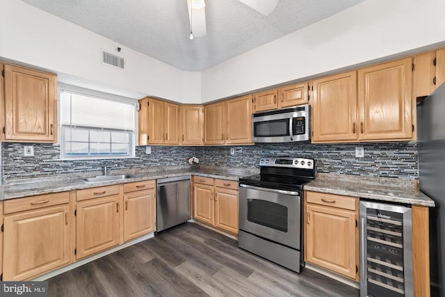 kitchen featuring light stone countertops, sink, stainless steel appliances, beverage cooler, and a high ceiling