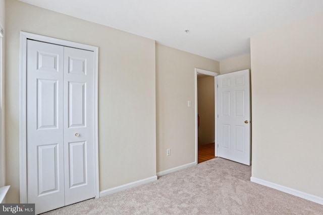 unfurnished bedroom with light carpet and a closet