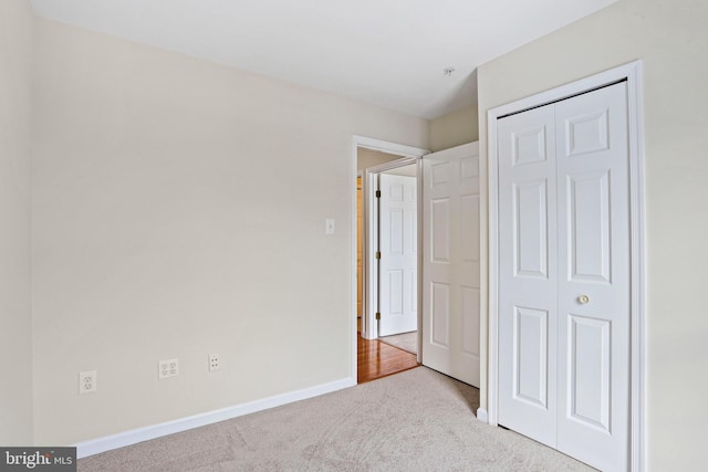 unfurnished bedroom featuring light carpet and a closet