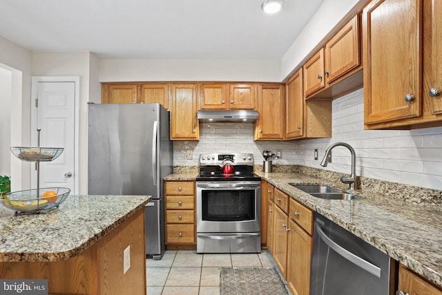 kitchen with tasteful backsplash, light stone countertops, sink, and appliances with stainless steel finishes