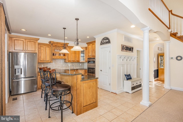 kitchen featuring stainless steel appliances, a kitchen bar, light tile patterned floors, dark stone counters, and a center island with sink