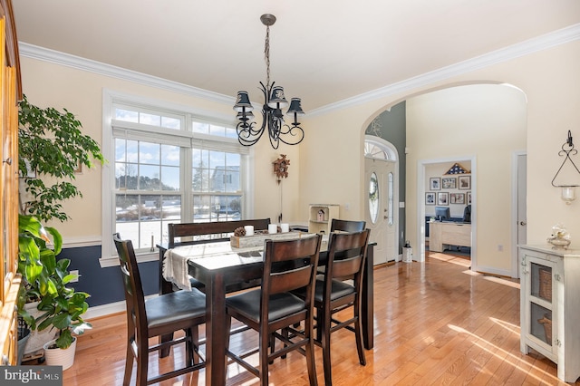 dining area featuring light hardwood / wood-style floors, crown molding, and a chandelier