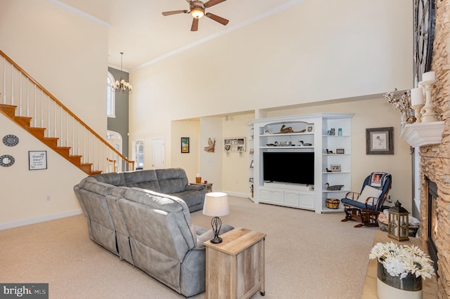 living room with a fireplace, light carpet, ceiling fan with notable chandelier, a high ceiling, and crown molding